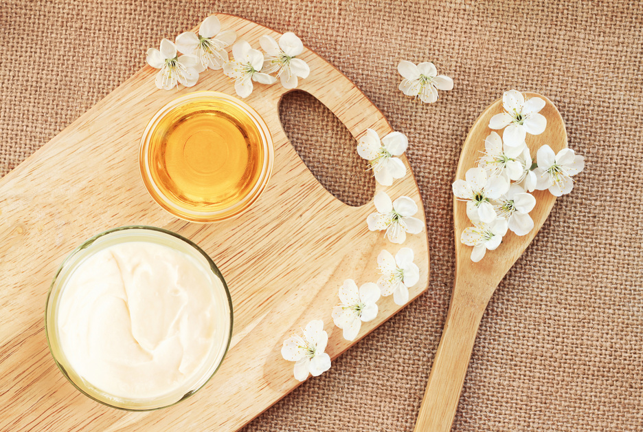 Natural skincare body butter cream, glass jar with honey, fresh blossom top view